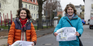 Christine Söhlke (links) und Anette Mecke zeigen die Pläne für den Bereich der Bachstraße. Hinter ihnen ist die geplante Sperrung, im Bereich des Spielplatzes, angedacht.