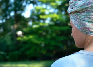 Was an Krebs Erkrankte tun können, um zum Behandlungsverlauf beizutragen Bild zeigt eine junge Frau mit einem bunten Kopftuch, die auf eine Wiese schaut.