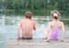 Zwei Kinder planschen im Wasser vom Steg aus