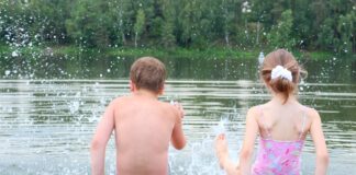 Zwei Kinder planschen im Wasser vom Steg aus