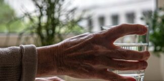 Ältere Person greift Wasserglas zum trinken