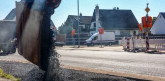 Baggerschaufel schüttet Teer in eine Baustelle