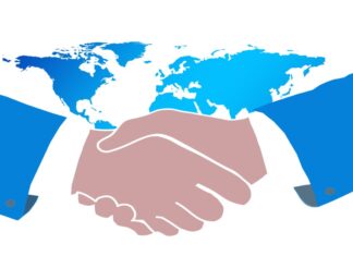 Zugangszahlen Geflüchteter nach Niedersachsen: Land setzt Zahl für die nächsten sechs Monate auf 70.000 fest und sagt weitere Erhöhung eigener Kapazitäten zu Grafik - Hände schütteln vor Weltkarte