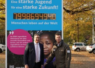 Deutsche Stiftung Weltbevölkerung (DSW) und Erlebnis-Zoo Hannover eröffnen DSW-Jugendklub-Ausstellung Jan Kreutzberg und Andreas M. Casdorff vor der Weltbevoelkerungsuhr auf dem Zoo-Parkplatz
