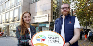 ÜSTRA Vorständin Denise Hain und Moritz Meyer, Kinderschutzallianz, erklären das GVH Kundenzentrum zur "Kinder:Schutzinsel"