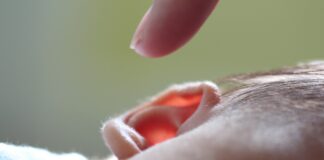 Finger zeigt auf Kinderohr