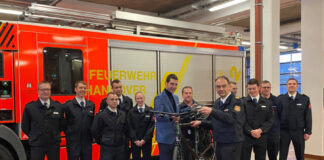 Neun Auszubildende starten ihre Karriere bei der Berufsfeuerwehr und werden von Dr. Axel von der Ohe (Feuerwehrdezernent), Christoph Bahlmann (Leiter der Feuerwehr) und Mario Kraatz (Vorsitzender des örtlichen Personalrats, im Hintergrund) begrüßt.