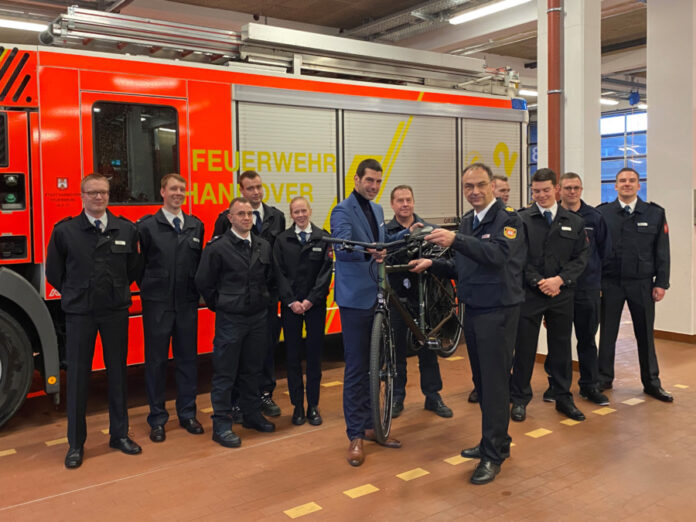 Neun Auszubildende starten ihre Karriere bei der Berufsfeuerwehr und werden von Dr. Axel von der Ohe (Feuerwehrdezernent), Christoph Bahlmann (Leiter der Feuerwehr) und Mario Kraatz (Vorsitzender des örtlichen Personalrats, im Hintergrund) begrüßt.