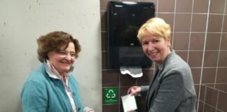 Zum Start des Pilotprojektes bringen Silke Kaune (li.) und Kirsten Grimm-Hose einen Aufkleber „Nur Papierhandtücher" an. Grund hierfür: Sie werden am Gymnasium Langenhagen ab sofort recycelt; der „Abfall“ muss daher sortenrein sein.