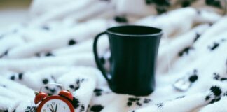 Uhr und Tasse auf Decke