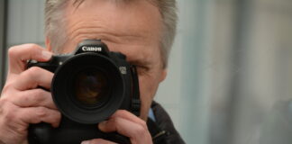 Mann hinter Kamera fotografiert