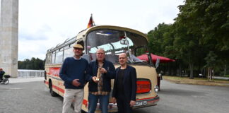 Die BussaNova Classic Tours-Inhaber Thorsten Stahl (v. l.) und Torsten Krüger nehmen von Jens Palandt, Klimadezernent der Region Hannover, den symbolischen Leuchtturm für die Förderung des Bus-Umbaus entgegen.