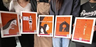 Fünf Schülerinnen des Wahlpflichtkurses „Logo und Design“ der IGS Süd präsentieren ihre Plakate, die sie im Rahmen der Kampagne zum „Orange Day“ gestaltet haben.