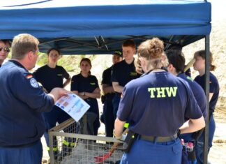 THW trainiert Hochwasserschutz und Deichverteidigung Technischer Berater Hochwasserschutz & Deichverteidigung Sven Quintel erklärt wie Sandsäcke bei der Aufkadung (Sandsackdamm) verlegt werden.