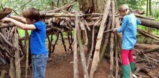 Kinder spielen im Wald / Hütte bauen