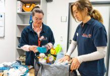 Notfallhilfe mit Herz: Kleiderkammer „Nahtstelle“ unterstützt Menschen in akuter Not Elena Böhnisch und Linda Valle beim Packen einer Babytasche.