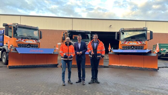 v.l.n.r. Julia Fürst (aha-Geschäftsführerin), Axel von der Ohe (Erster Stadtrat und Finanz- und Ordnungsdezernent), Simon Grabow (Leiter der Stadtreinigung von aha) vor Schneepflügen, die sich bereit machen zum Winterdienst-Training.