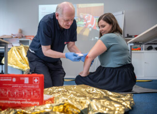 Gut vorbereitet in Krisenzeiten: Johanniter stärken Katastrophenvorsorge in Hannover Ein Erste Hilfe-Trainer zeigt am Beispiel einer Teilnehmerin in einem Erste Hilfe-Kurs, wie man einen Verband am Ellenbogen anlegt.