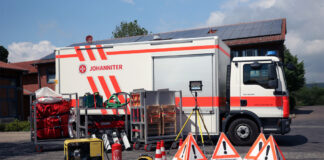 Ein Gerätewagen Sanität (GW-SAN) der Johanniter mit Teilen seines Materials davor.