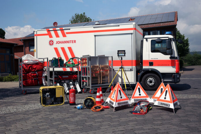 Ein Gerätewagen Sanität (GW-SAN) der Johanniter mit Teilen seines Materials davor.