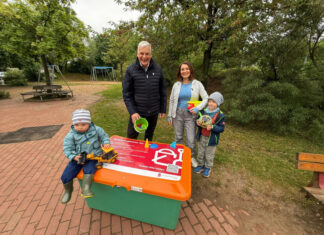 Erste Sandspielzeugkiste auf Spielplatz in Langenhagen eröffnet Vom Wunsch zur Wirklichkeit: Erste Sandspielzeugkiste in Langenhagen eröffnet. Hinter der Kiste, v.l.n.r. Mirko Heuer, Annelie Dobewall mit KIndern.