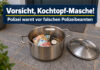 ki-generiertes symbolbild - polizeiwarnung für falschen polizeibeamten: vor einer geschlossenen haustür steht ein offener kochtopf mit geldscheinen, einer armbanduhr und einer goldfarbenen kette. der deckel liegt daneben.